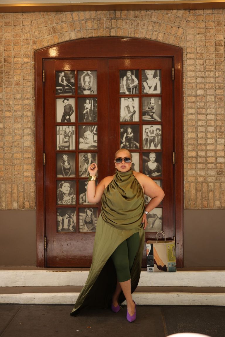 Suzanne Ujaque con un vestido de satén verde oliva frente a un teatro de Broadway en Nueva York